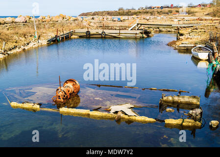 Old wreckage of pram in a small harbor. Parts of rusted winch sticking up over the water surface. Location Aleklinta on Oland, Sweden. Stock Photo