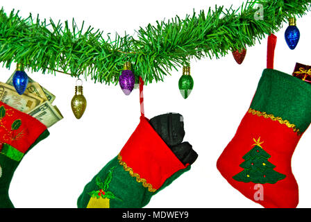 Lump of coal and money in Christmas  stockings hanging on green garland and glitter light string Stock Photo