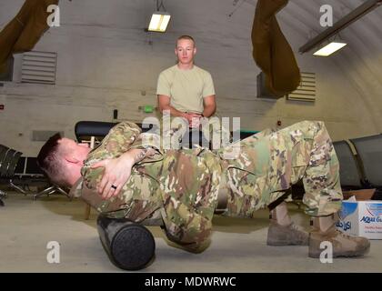 Staff Sgt. David Dillow, 386th Expeditionary Medical Group physical therapy technician, teaches Senior Airman Calvin Lourens, 386th Expeditionary Logistics Readiness Squadron passenger service specialist, techniques to help relieve his pain Dec. 7, 2017, at an undisclosed location in Southwest Asia. (U.S. Air Force photo by Tech. Sgt. Louis Vega Jr.) Stock Photo