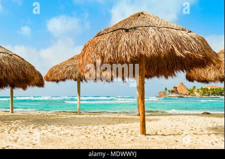 Grass beach umbrellas next to the Caribbean ocean; Playa Del Carmen, Quintana Roo, Mexico Stock Photo