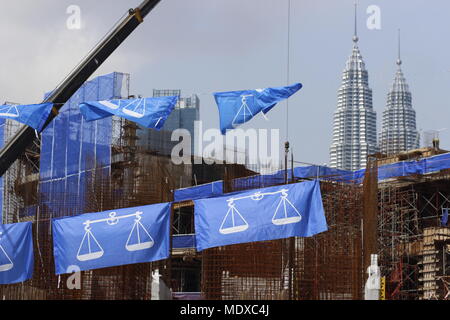 Kuala Lumpur, Malaysia. 21st April, 2018. The upcoming May 2018 general elections is expected to be a keenly contested fight between the ruling coalition party and the opposition alliance. Blue flags seen here belong to the ruling party Barisan Nasional. A building under construction and the Petronas Twin Towers can be seen in the background. Credit: Beaconstox/Alamy Live News. Stock Photo