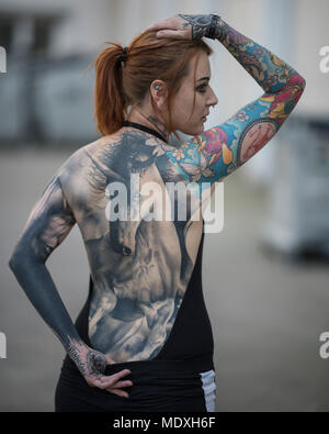 Frankfurt, Germany. 21st April, 2018.  a woman presents her unicorn back tattoo at a tattoo convention where tattoo artists and enthusiasts travel from far and wide to exchange ideas, techniques and knowledge. Photo: Boris Roessler/dpa Credit: dpa picture alliance/Alamy Live News Stock Photo