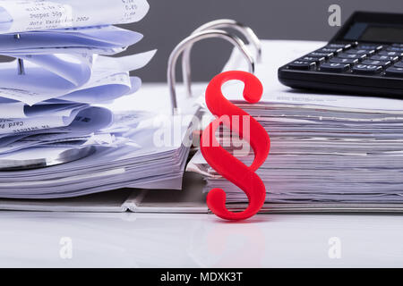 Close-up Of Red Paragraph Symbol Leaning On Documents