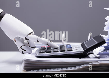 Close-up Of A Robotic Hand Calculating Bills Using Calculator In Office Stock Photo