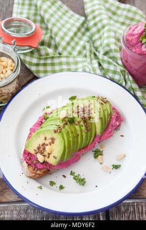 Slice of bread with red beet hummus and fresh avocado Stock Photo