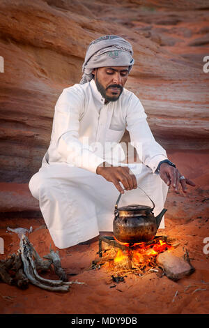 Young Bedouin man prepare traditional tea on the fire, Wadi Rum Desert, Jordan Stock Photo