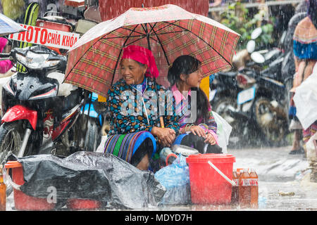 Hmong women at the Sunday market in the rain; Bac Ha, Lao Cai, Vietnam Stock Photo