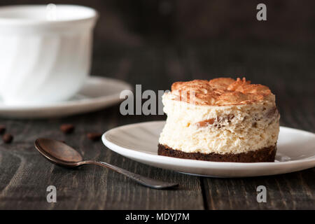 Tiramisu cake on a white saucer and a cup of black coffee Stock Photo