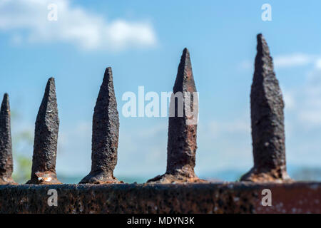 Old iron prison spikes and blue sky. Selective focus, close up Stock Photo