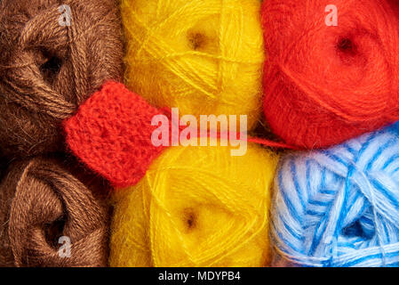 Rows of bright multi-colored tangles of knitting threads and a pattern close-up. Stock Photo