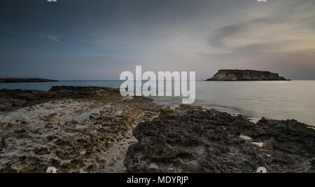 Rocky Seascape at dramatic sunset with the small  island of Geronisos at Paphos area Akamas peninsula in Cyprus Stock Photo