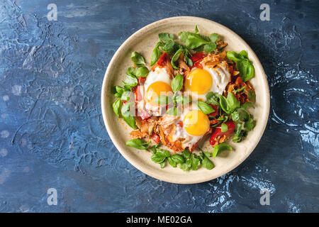 Traditional Israeli Cuisine dishes Shakshuka. Fried egg with vegetables tomatoes and paprika in ceramic plate over blue texture background. Top view,  Stock Photo