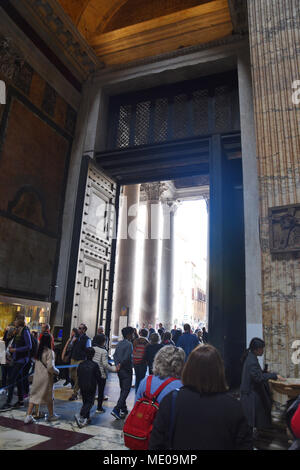 Tourists exit through the large bronze doors from the 15th century. The Pantheon is a former Roman temple, now a church, in Rome. The present building Stock Photo