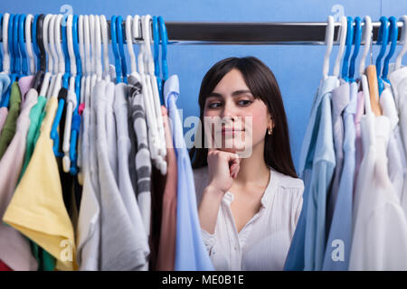 Young Woman Looking At Clothes On Clothes Rail In Store Stock Photo
