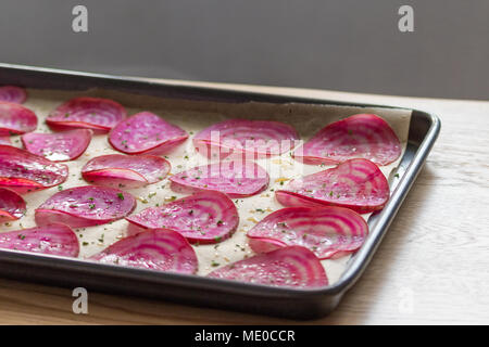 Slices of candy beetroot (chioggia beets) on a lined baking tray, ready for making oven-baked veggie chips. Stock Photo