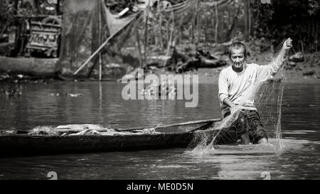 A man smoking a cigarette while fishing from his boat on the Mekong River, Mekong Delta; Thoi An, Can Tho, Vietnam Stock Photo