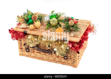 Closed Wicker basket overflowing with red and gold tinsel with Christmas decorations resting on the lid Stock Photo