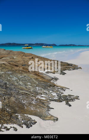 Rock formations and white sand on Whitehaven Beach with anchored boats along Whitsunday Islands in Queensland, Australia Stock Photo