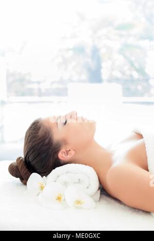 Young woman lying on towel in spa, eyes closed. Stock Photo