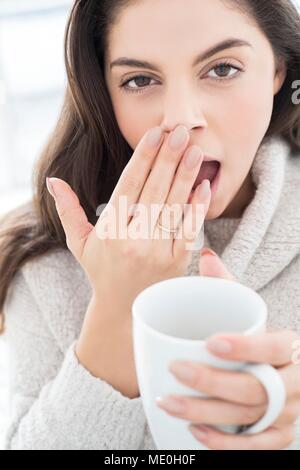 Young woman with mug, yawning. Stock Photo