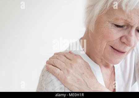 Senior woman rubbing sore shoulder. Stock Photo