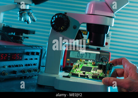 Examining circuit board with microscope. Stock Photo