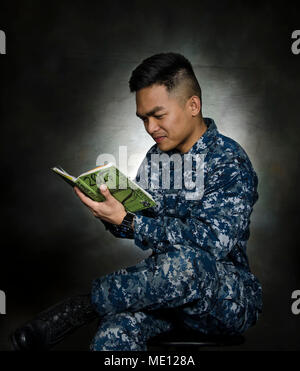 PORTLAND, Ore. (Dec 5, 2017) – Personnel Specialist 2nd Class John Paul T. Delossantos, the submarine tender USS Frank Cable's (AS 40) Junior Sailor of the Year, from Manila, Republic of the Philippines, reads through his secret weapon to prioritizing and balancing his work flow, while in the ship's studio, Dec. 5. Frank Cable is currently completing a dry-dock phase maintenance availability. The ship will get underway soon for sea trials, which constitutes the final determination of a ship’s ability to re-join the fleet as an operational unit to conduct maintenance and support submarines and  Stock Photo