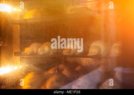 A close-up of the process of making croissants and puff pastry in the oven at a high temperature in a bakery Stock Photo