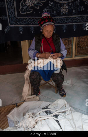 Dali, China - March 23, 2018: Bai woman hand dyeing fabrics with indico blue Stock Photo