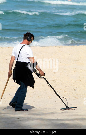 Man using a metal detector at a beach on the Gold Coast in Australia Stock Photo