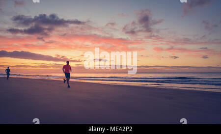 Two runners are running on the beach at sunrise. Stock Photo