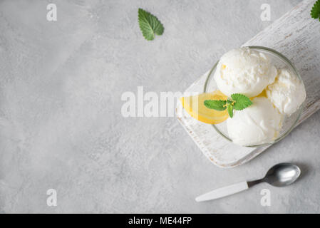 Lemon Ice Cream in bowl. Homemade citrus lemon ice cream with mint on grey background with copy space. Stock Photo