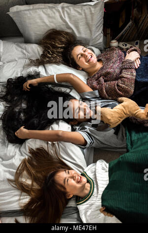 Teenage girls lying on the bed together with stuffed animal childhood and friendship concept Stock Photo