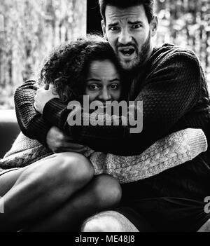 Young couple watching scary movie together Stock Photo