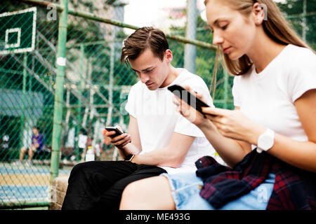 Expressionless young couple in the park using smartphones with no social interactions addiction concept Stock Photo