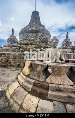 A Buddha statue with the hand position of dharmachakra mudra in an opened perforated stupa on the circular top terrace of 9th century Borobudur Buddhi Stock Photo