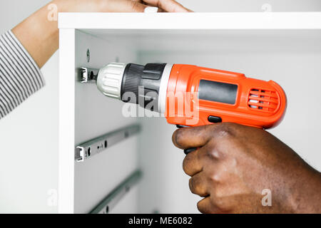 Man using electronic drill install cabinet Stock Photo