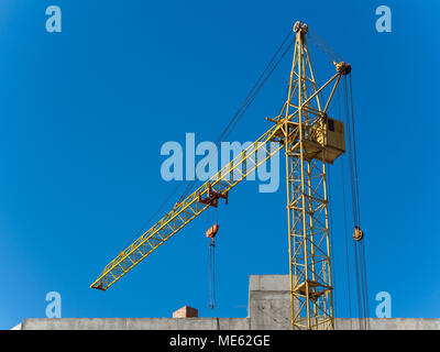 working yellow crane with the blue sky on the background Stock Photo