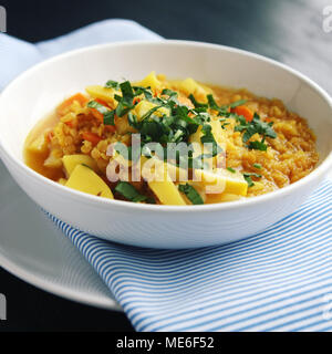 Red lentil stew with potato, carrot and turmeric. Toned photo. Healthy lunch on the round white plate. Colorful vegan dish with potato, carrot and tur Stock Photo