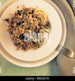 Millet with mushrooms and spinach. Vegan dish. Vegetarian couscous on the round white plate. Top view. Toned photo. Stock Photo
