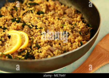 Vegetarian couscous with mushrooms and spinach. Vegan dish with millet in the frying pan. Close up. Stock Photo
