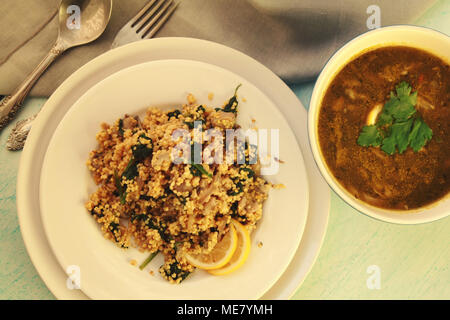 Millet with mushrooms and spinach. Vegan dish. Vegetarian couscous on the round white plate. Top view. Stock Photo