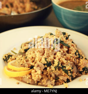 Millet with mushrooms and spinach. Jewish cuisine. Vegetarian couscous on the round white plate. Close up. Toned photo. Stock Photo