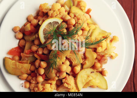 Vegetable stew with chickpeas, cauliflower and cabbages. Close up. Top view. Vegan dish. European cuisine. Vegetarian lunch. Toned photo. Stock Photo