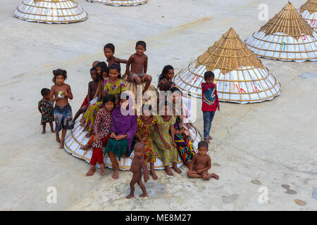 Workers in a rice mill shelter their product with pyramid-shaped covers. Stock Photo