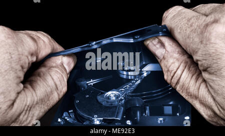 Dirty hands and hard disk drive. Computer saboteur with open storage device. Concept of cybercrime, spy, theft, hacking, manipulation, data protection. Stock Photo