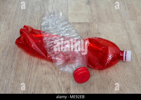 Red and white plastic bottle on wood floor. Two used squeezed PET bottles on wooden background. Ecological sorting and disposal of household waste. Stock Photo