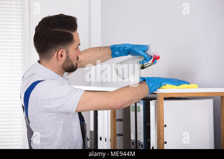 Close-up Of A Young Male Cleaner Cleaning Shelf At Workplace Stock Photo