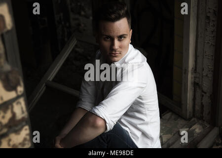 Close up view of brutal man crouching in the abandoned place. Stock Photo
