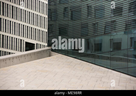 An exposure of the roof of the opera in Oslo, with a business building behind and reflection of another business building in the large windows Stock Photo